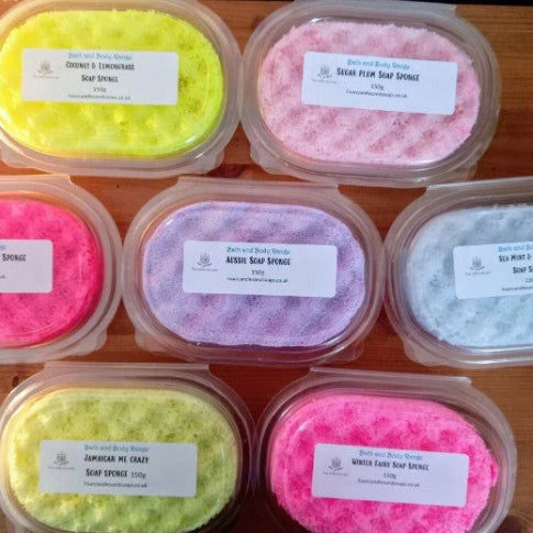 Assorted coloured soap samples in plastic containers on a wooden surface. Four Candles and soaps