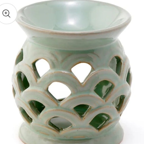 Light green ceramic oil burner with intricate lattice design on a white background