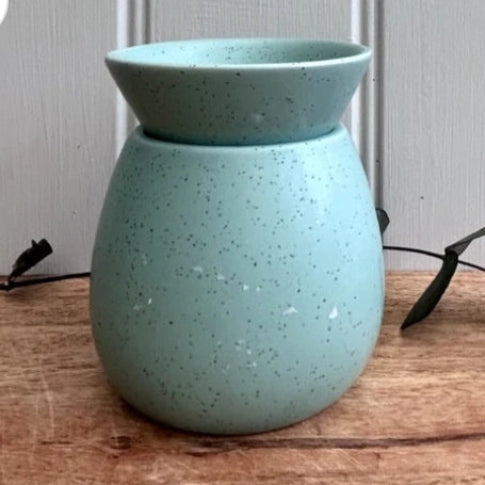Speckled blue ceramic diffuser on a wooden surface with a neutral background