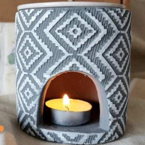 Ceramic lantern with geometric pattern holding a lit candle on a neutral background